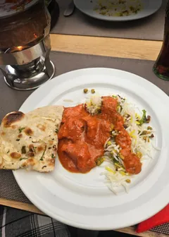 Butter chicken with rice and naan on a white plate