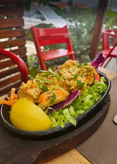 Chicken tikka on a sizzling plate with salad and lemon